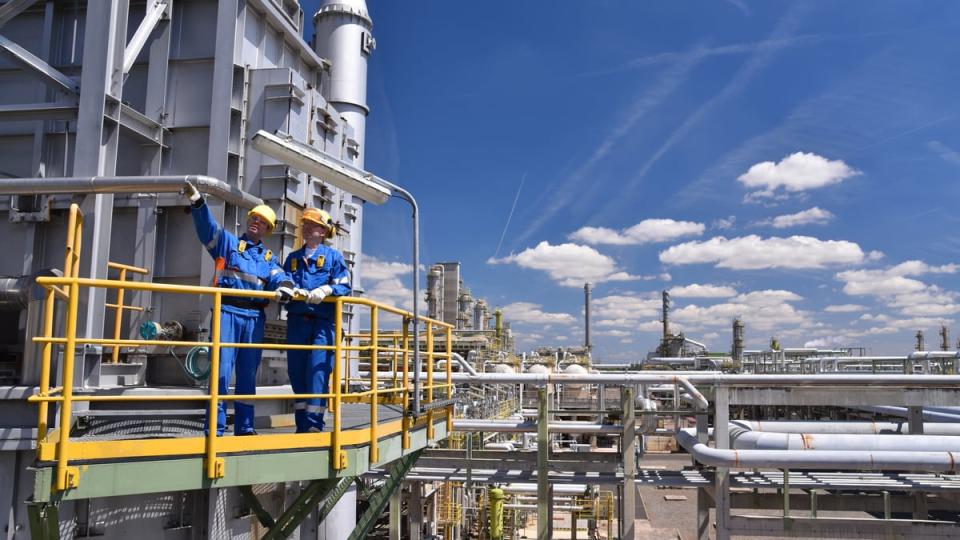 Two people wearing personal protective equipment at an oil refinery. 