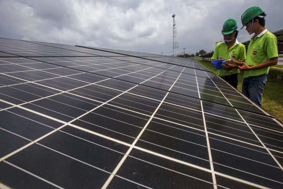 Employees of a solar farm company take notes between panels at the farm in Nakorn Ratchasima province, Thailand, October 3, 2013. Come December, Thailand will have more solar power capacity than all of Southeast Asia combined as record sums of money is poured into the sector in the hopes of nurturing a new energy source to help drive the region's second-biggest economy. To match story THAILAND-SOLAR/ Picture taken October 3, 2013. REUTERS/Athit Perawongmetha