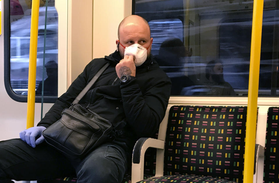 A man wears a mask and a glove as he travels on the tube in London, Friday, March 13, 2020. For most people, the new coronavirus causes only mild or moderate symptoms, such as fever and cough. For some, especially older adults and people with existing health problems, it can cause more severe illness, including pneumonia. (AP Photo/Kirsty Wigglesworth)