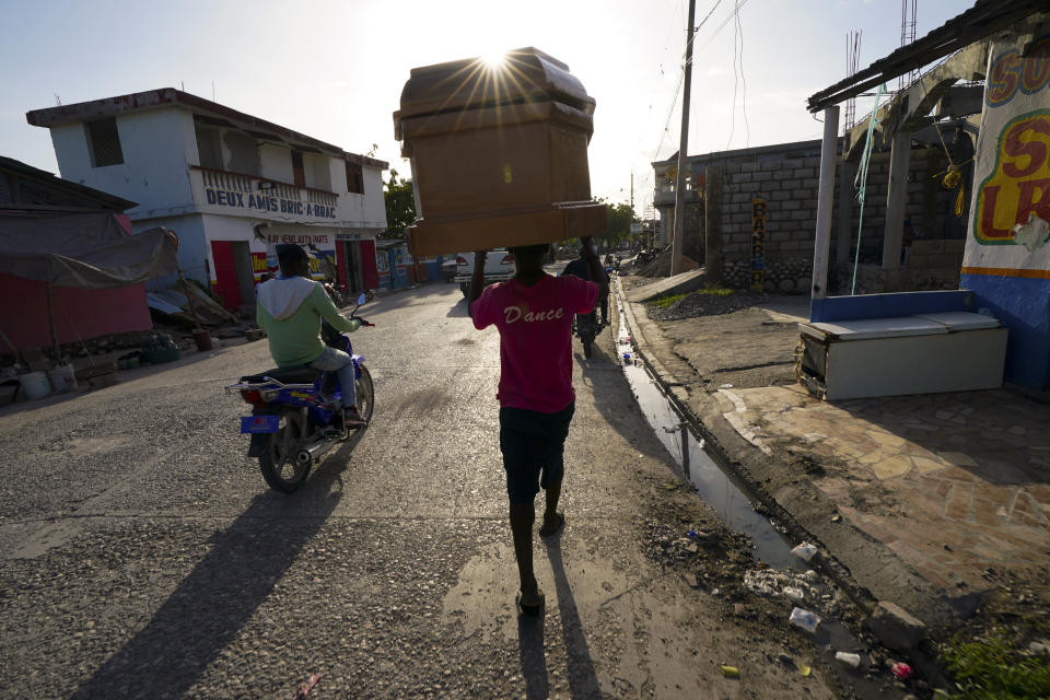 A worker carries a coffin form a storage depot to a funeral home in Les Cayes, Haiti, Wednesday, Aug. 18, 2021. A 7.2-magnitude earthquake struck the southwestern part of the hemisphere's poorest nation on Aug. 14. (AP Photo/Fernando Llano)