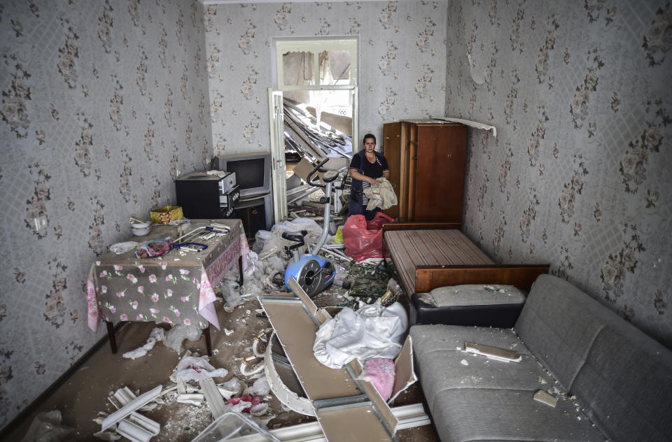 FILE - In this Oct. 13, 2020, file photo, a woman stands inside her damaged house two days after shelling by Armenian's artillery in Ganja, Azerbaijan. A Russian attempt to broker a cease-fire to end the worst outbreak of hostilities over the region of Nagorno-Karabakh in more than a quarter-century has failed to get any traction, with Azerbaijan and Armenia trading blame for new attacks. (Ismail Coskun/IHA via AP, File)