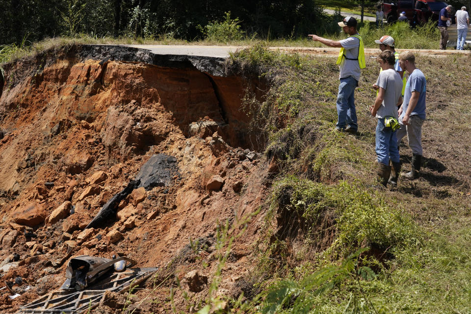 Mississippi Department of Transportation workers look at the deep hole on Mississippi Highway 26 in the Crossroads community, Tuesday, Aug. 31, 2021. Two people were killed and at least 10 others were injured when seven vehicles plunged, one after another, into the deep hole on the dark rural two-lane highway, which collapsed after Hurricane Ida blew through Mississippi. (AP Photo/Rogelio V. Solis)