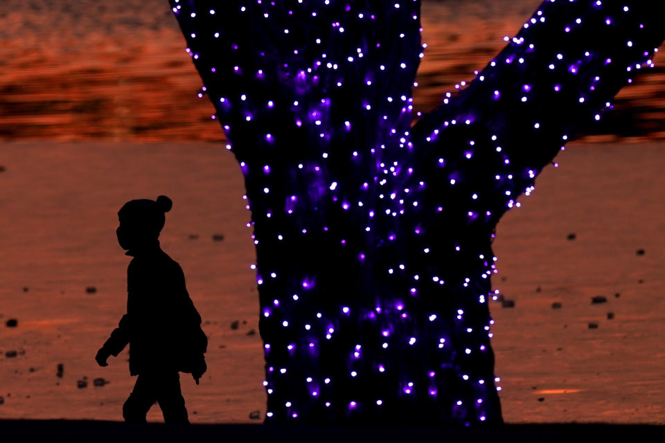 A boy wears masks to prevent the spread of the coronavirus as he looks at a holiday display on a mild day Saturday, Dec. 26, 2020, in a park in Lenexa, Kan. (AP Photo/Charlie Riedel)