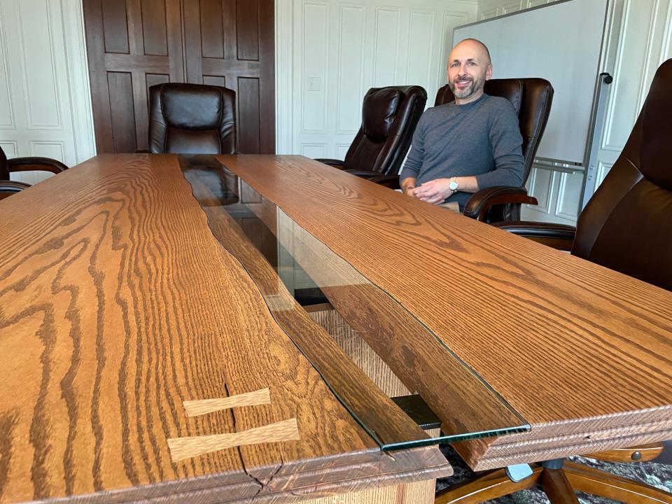 Garrett Roberson sits at a red oak table he crafted for the McPherson Mansion on Thursday, Dec. 14, 2023.