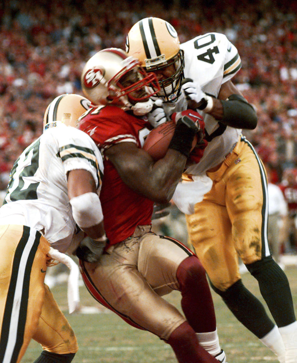 FILE - In this Jan. 3, 1999, file photo, San Francisco 49ers' wide receiver Terrell Owens pulls in a 25-yard touchdown pass from quarterback Steve Young as Green Bay Packers' safeties Pat Terrell (40) and Darren Sharper defend late in the fourth quarter of an NFC wild card playoff game at 3COM Park in San Francisco. Owens' catch with three seconds left in the game led the 49ers to a 30-27 win. The two teams that have combined for nine Super Bowl titles will meet with a spot in the ultimate game on the line once again when the 49ers (14-3) host the Packers (14-3) in the NFC championship game on Sunday, Jan. 19, 2020. (AP Photo/Susan Ragan, File)