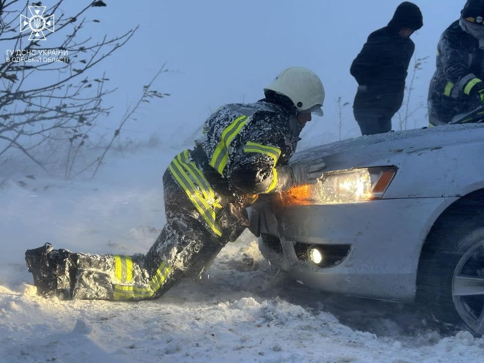 This handout photograph taken and released by Ukrainian Emergency Service on November 27, 2023, shows a rescuer pushing a car during heavy snowfall in Odesa region (UKRAINIAN EMERGENCY SERVICE/AFP)