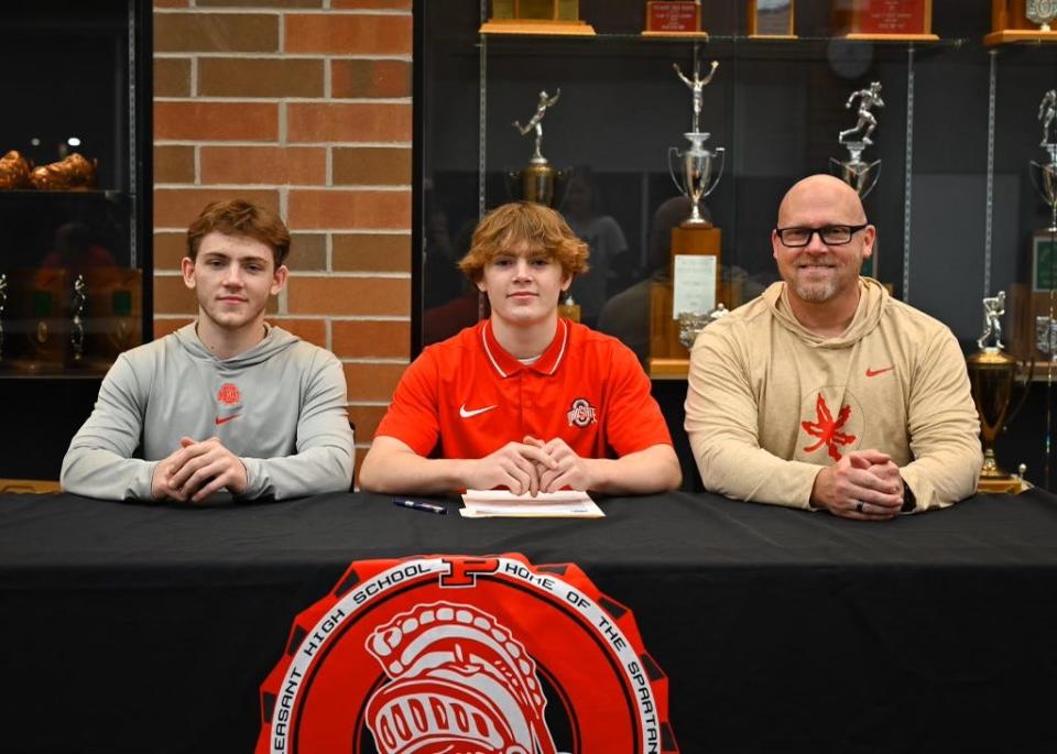 Pleasant senior wrestler Daxton Chase (center) is flanked by his brother Carter and father Steve at his commitment ceremony at the school earlier this month.