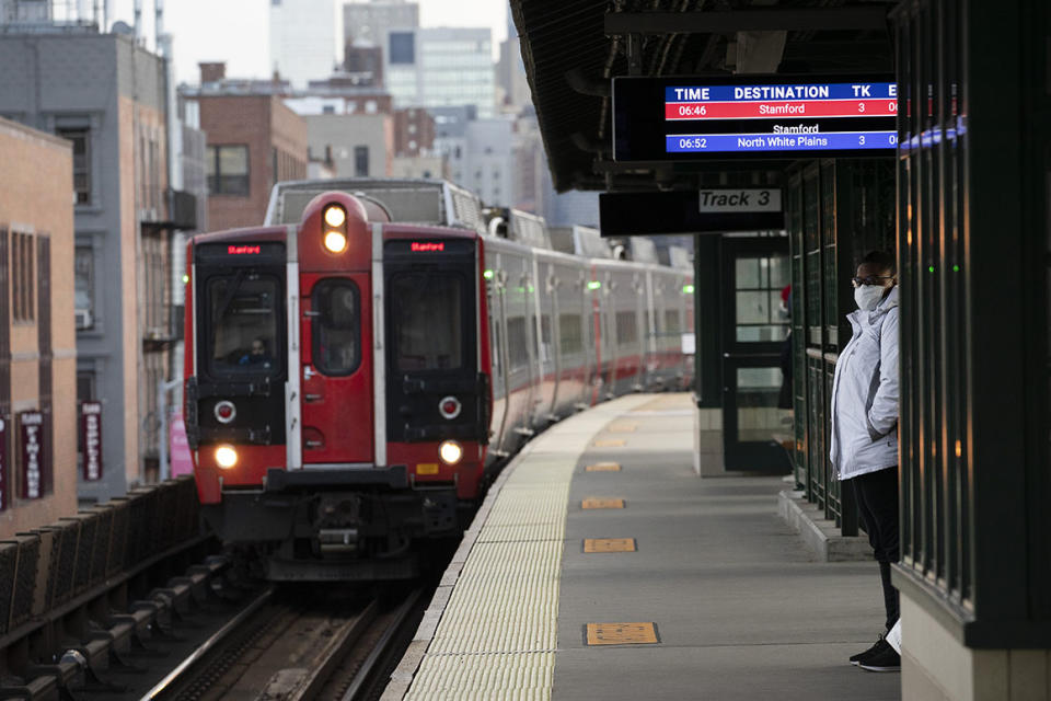 A woman wearing a mask waits for a train on a Metro-North Railroad platform at the 125th Street station, Thursday, April 16, 2020, in New York. The Metropolitan Transportation Authority, which has lost more than 90% of its riders, including on Metro-North, could take an $8.5 billion hit from the coronavirus, and needs another $3.9 billion in federal aid to stay afloat, MTA officials said Thursday. (AP Photo/Mark Lennihan)