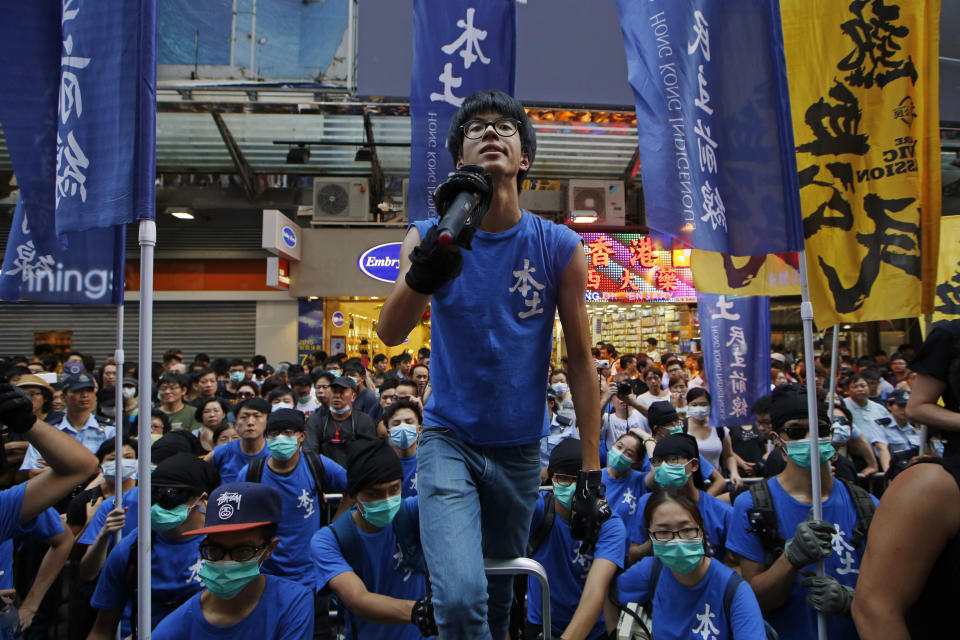 In this Saturday, July 11, 2015 photo, Ray Wong Toi-yeung, center, member of Hong Kong Indigenous group shouts slogan during a demonstration in Hong Kong. Germany has granted asylum to two Hong Kong activists in a sign of growing concern over how dissent is dealt with in the territory. (AP Photo/Kin Cheung)