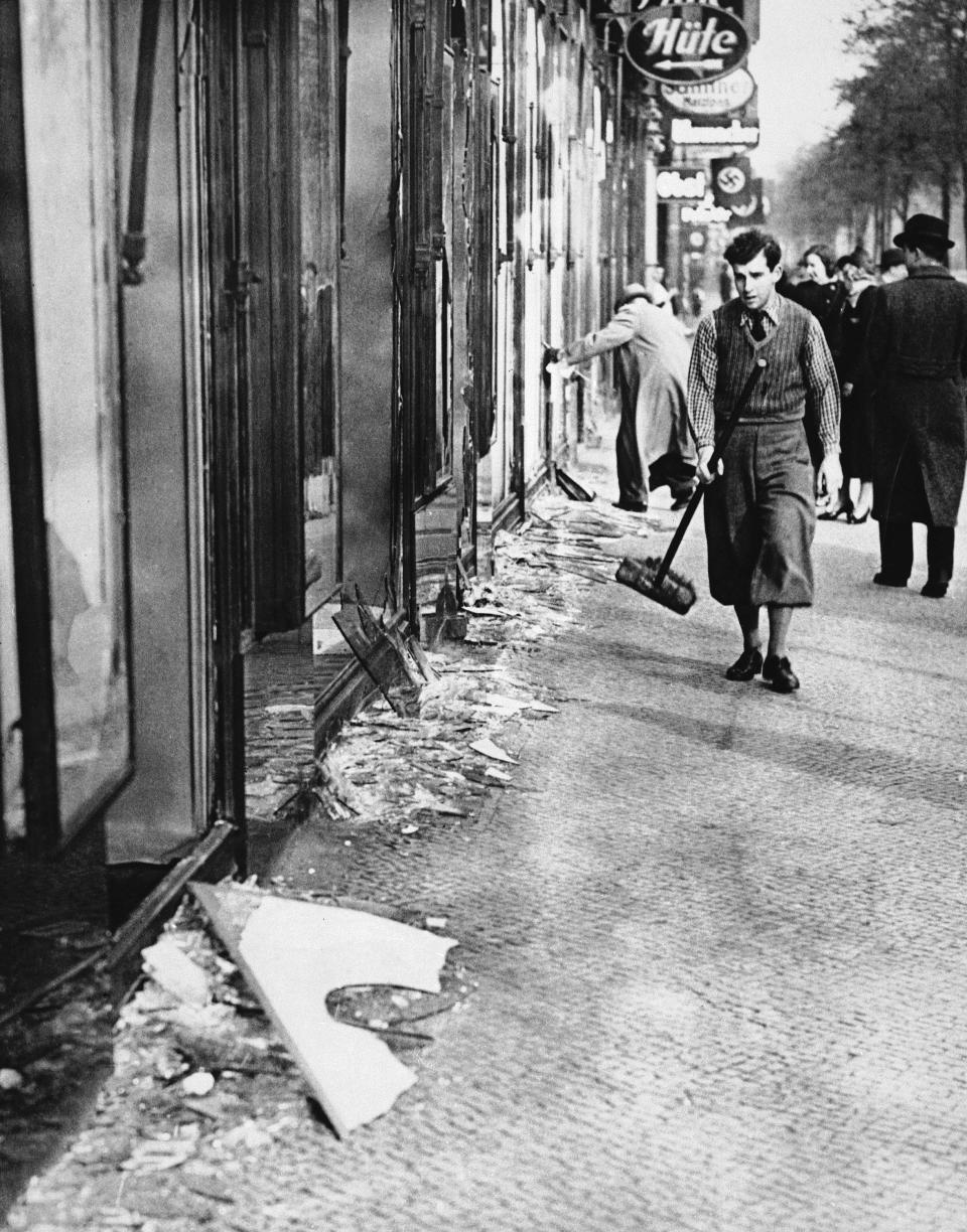 A young man with a broom clears broken glass from shop windows in Berlin, the morning after the Nazis demolished thousands of Jewish facilities during the night, in what was later called "Crystal Night" or "The Night of Broken Glass," Nov. 10, 1938.