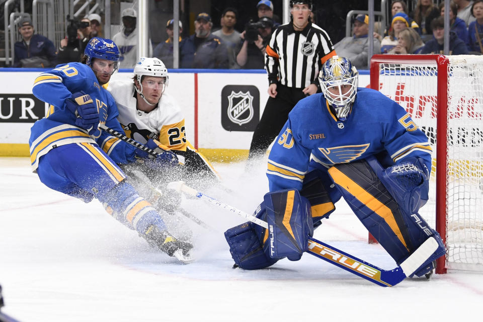 St. Louis Blues goaltender Jordan Binnington (50) and Brandon Saad (20) defend the net from the Pittsburgh Penguins' Brock McGinn (23) during the first period of an NHL hockey game, Saturday, Feb. 25, 2023, in St. Louis. (AP Photo/Jeff Le)