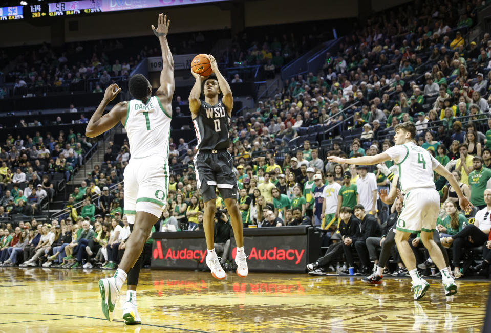 Washington State forward Jaylen Wells (0) shoots a three pointer against Oregon center N'Faly Dante (1) during the second half of an NCAA college basketball game in Eugene, Ore., Saturday, Feb. 10, 2024. Washington State beat Oregon 62-56.(AP Photo/Thomas Boyd)