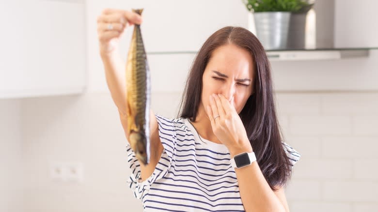 Woman holding smelly fish up