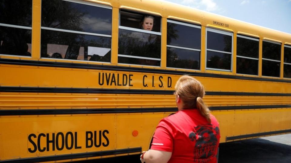 Una maestra habla con una madre desde un bus escolar en Uvalde, Texas