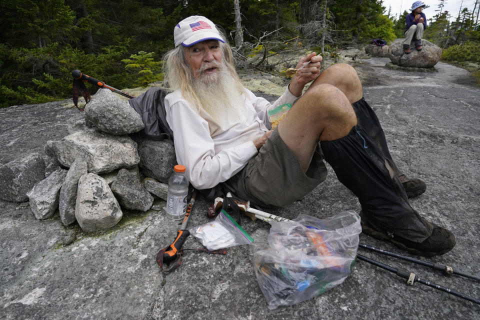 M.J. Eberhart, 83, scoops peanut butter out of a plastic bag during a lunch break on Mount Hayes on the Appalachian Trail, Sunday, Sept. 12, 2021, in Gorham, New Hampshire. Eberhart, who goes by the trail name of Nimblewill Nomad, is the oldest person to hike the entire 2,193-mile Appalachian Trail. (AP Photo/Robert F. Bukaty)