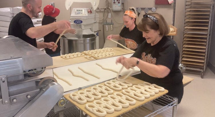 "People around here are passionate about sports and pretzels, and they go together," said Brian Kean, co-owner of The Philly Pretzel Factory in Langhorne. From left, Kean, his brother, Shaun (on phone, multitasking), morning manager Kristen Hargraves, and Linda Kean (foreground) The Keans' mother