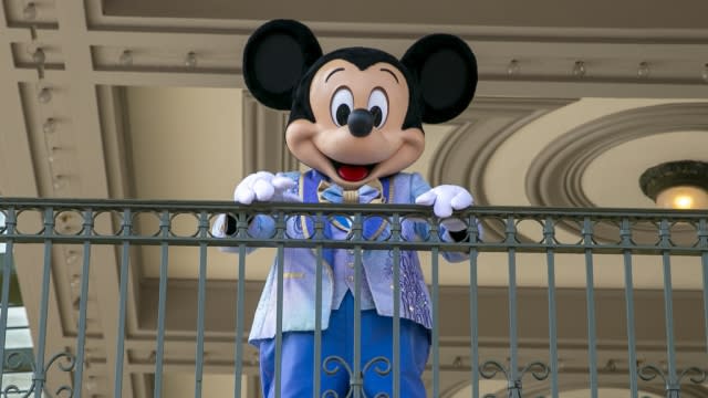 An actor dressed as Mickey Mouse greeting visitors at Walt Disney World.