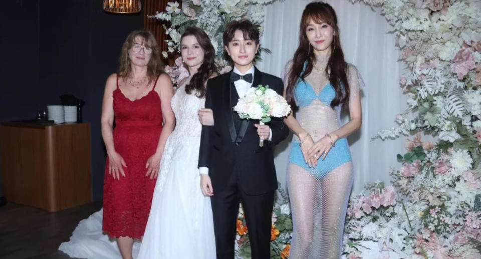 Mother of the bride in a bikini with a sheer covering (far right) and from left the other mother of the bride and the happy couple.