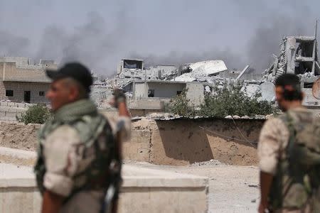 Syria Democratic Forces (SDF) fighters look towards rising smoke from damaged buildings in Manbij, in Aleppo Governorate, Syria, August 7, 2016. REUTERS/Rodi Said