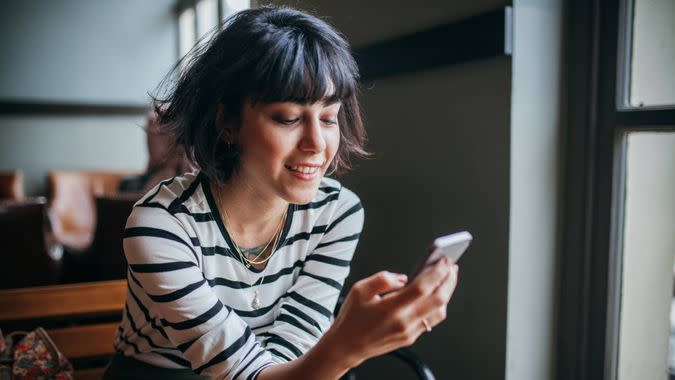 Happy woman using phone at cafe.