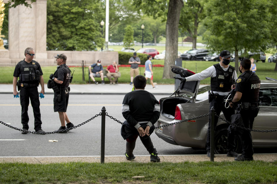 Lewis Sanchez, center, sits after being handcuffed by Secret Service agents along Constitution Avenue near the White House in the morning as protests continue over the death of George Floyd in Washington, Tuesday, June 2, 2020. Floyd died after being restrained by Minneapolis police officers. Sanchez and three other friends were stopped as they returned to their car after spending the night at a strangers home because of a District of Columbia city wide curfew. Agents later released Sanchez. (AP Photo/Andrew Harnik)