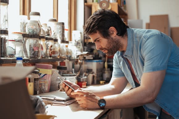 Young craftsman ordering materials on a tablet in his workshop.