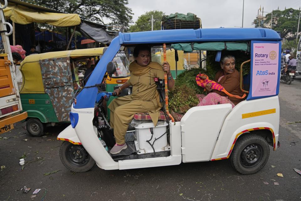 An elderly lady with a load of vegetables travels in an electric auto rickshaw driven by Preethi, a 38-year-old transgender woman who uses only her first name, in Bengaluru, India, Monday, July 10, 2023. “I have regular customers who range from vegetable vendors to mothers in my neighborhood who prefer to send their daughters to schools and colleges with me,” said Preethi. (AP Photo/Aijaz Rahi)