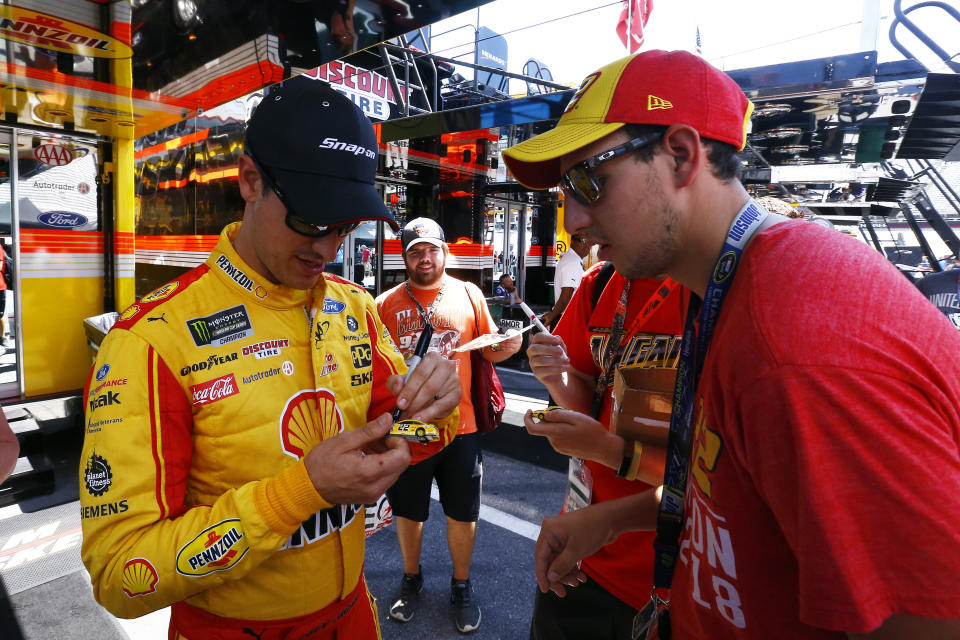 Driver Joey Logano signs autographs as he walks through the pits before practice for a NASCAR Cup Series auto race, Friday, Aug. 16, 2019, in Bristol, Tenn. (AP Photo/Wade Payne)