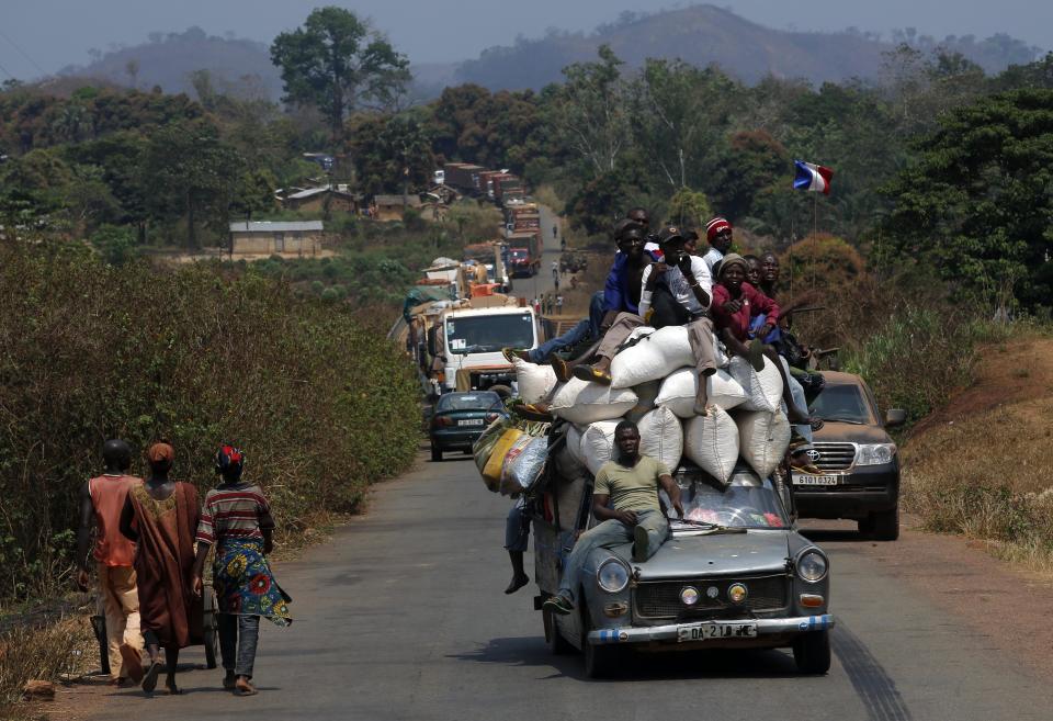 A vehicle filled with people and heavy load, precedes a convoy of over 100 trucks arriving in the Central African Republic capital Bangui from Cameroon, Monday Jan. 27, 2014. The trucks were loaded with military logistic for French forces and Humanitarian aid for the Word Food Program. (AP Photo/Jerome Delay)