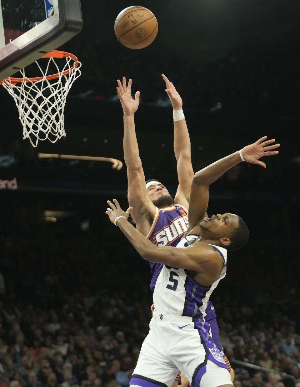 Sacramento Kings guard De'Aaron Fox (5) is fouled by Phoenix Suns guard Devin Booker (1) during the third quarter of a game at Footprint Center in Phoenix on Feb. 13, 2024.