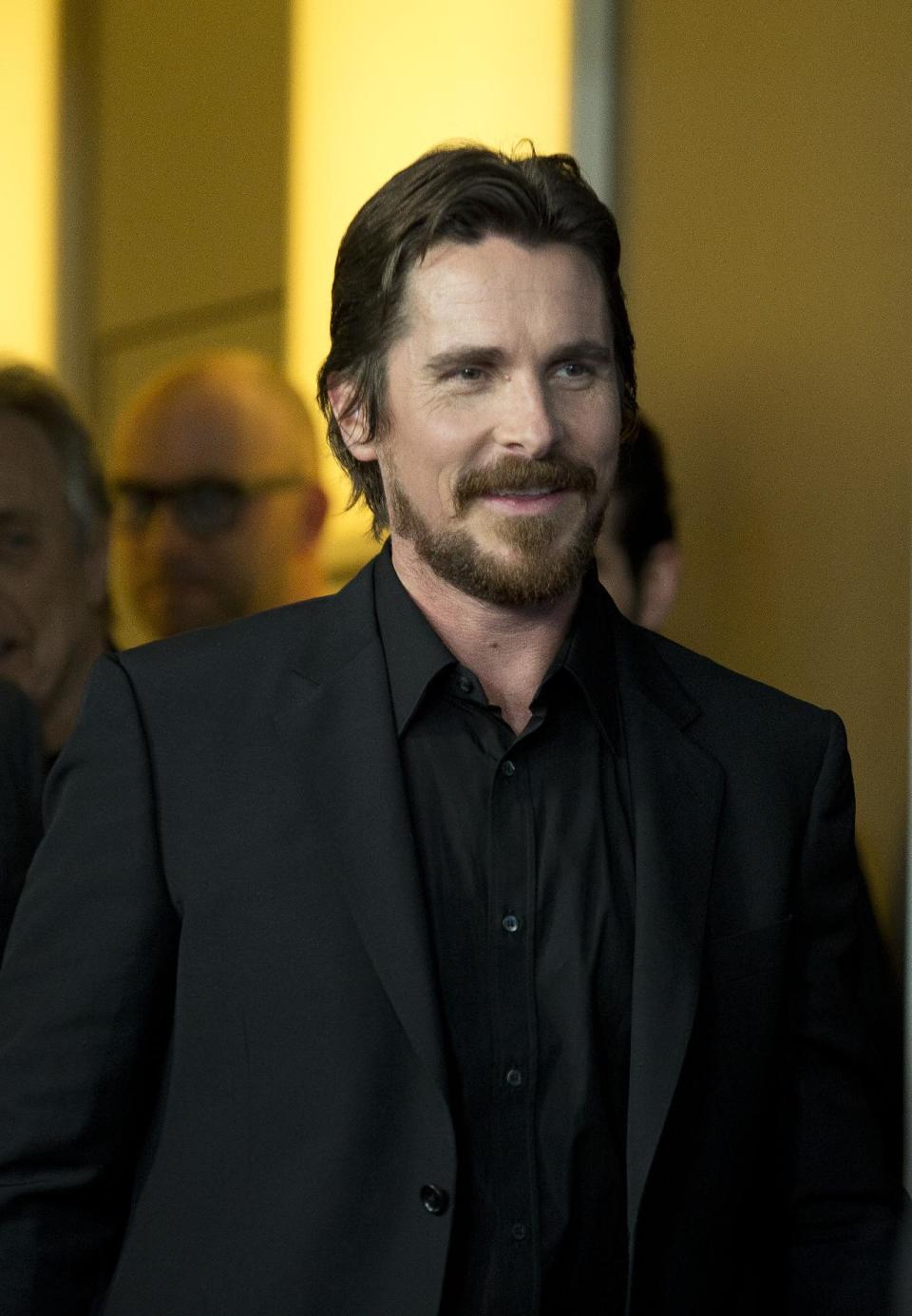 Actor Christian Bale jokingly arrives at the photo call for the film American Hustle during the International Film Festival Berlinale, in Berlin, Friday, Feb. 7, 2014. (AP Photo/Axel Schmidt)
