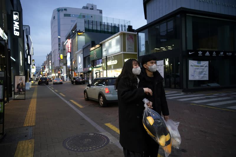 A couple wearing masks to prevent contracting the coronavirus walks at Dongseong-ro shopping street in central Daegu