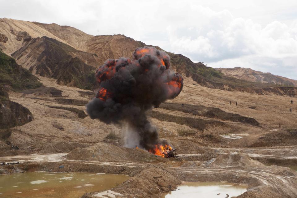 A cloud of smoke blossoms from the controlled explosion of machinery used for illegal mining is seen in Huepetuhe district in Peru's Madre de Dios region in Peru, Monday, April 28, 2014. Some 1,500 soldiers, police and marines have begun destroying illegal gold mining machinery in Peru’s southeastern jungle region of Madre de Dios. Authorities began enforcing a ban on illegal mining in the district. They had given the state’s illegal miners until April 19 to get legal or halt operations. (AP Photo/Rodrigo Abd)