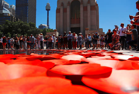Members of the public place floating poppies onto a pond during a memorial service at the ANZAC Memorial to mark the centenary of the Armistice ending World War One, in Sydney, Australia, November 11, 2018. REUTERS/David Gray