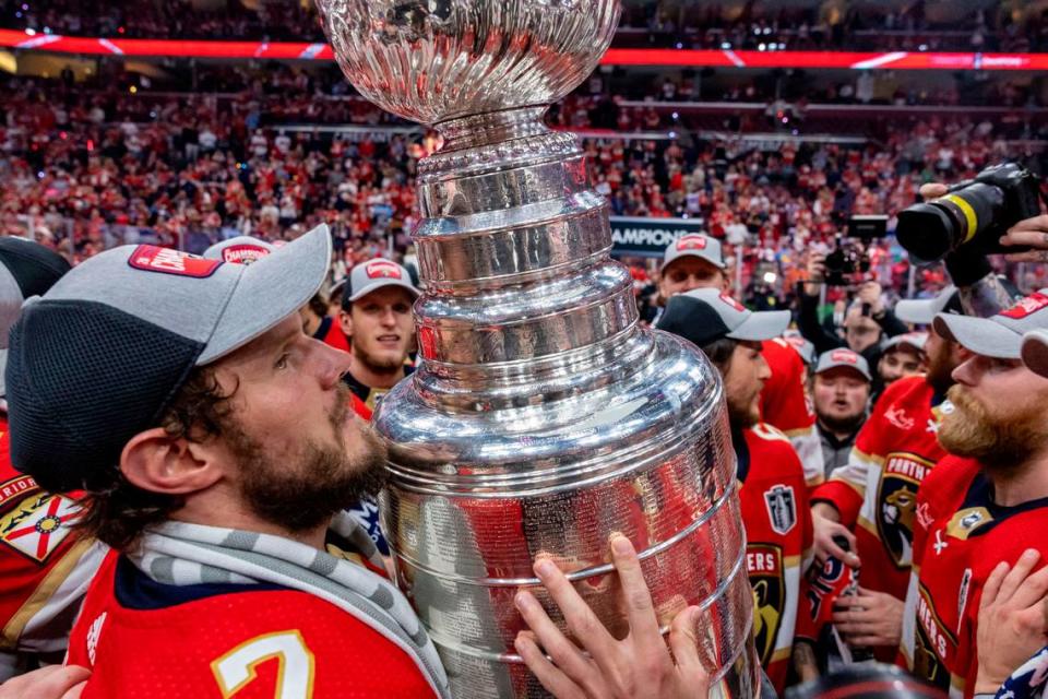 Sunrise, Florida, June 24, 2024 - Dmitry Kulikov (7), left, hugs the Stanley Cup as other Panther players gather around the trophy during the celebration after game 7 of the Stanley Cup Final