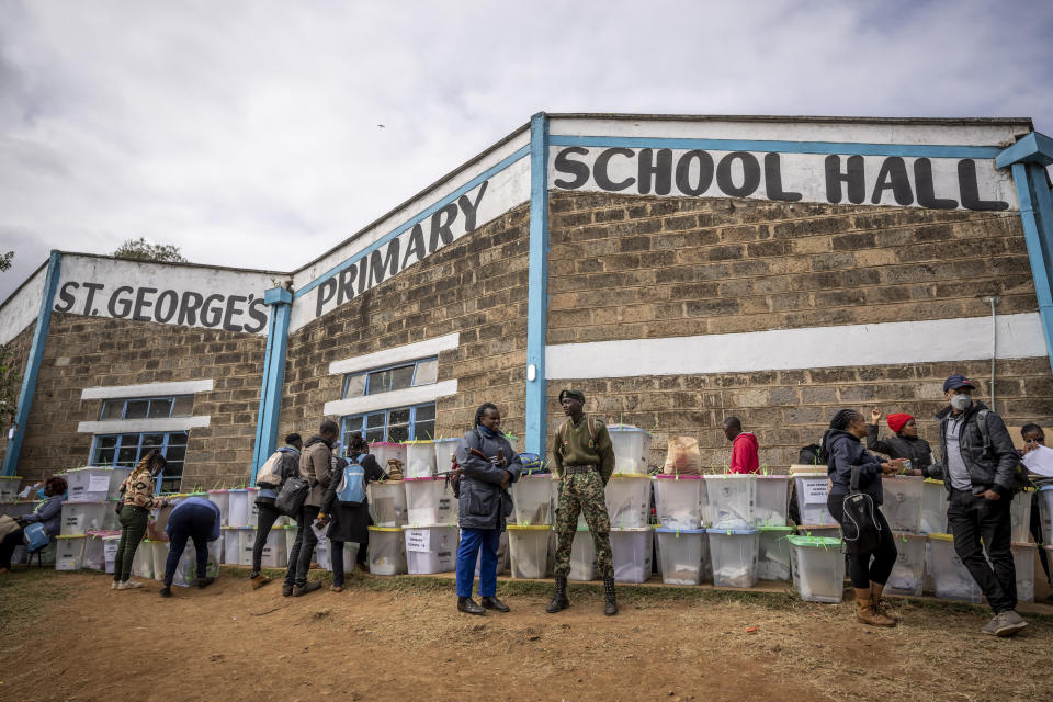 Electoral workers and security forces stand next to ballot boxes lined up and ready to be stored at a collection and tallying center in Nairobi, Kenya Wednesday, Aug. 10, 2022. Kenyans are waiting for the results of a close but calm presidential election in which the turnout was lower than usual. (AP Photo/Ben Curtis)