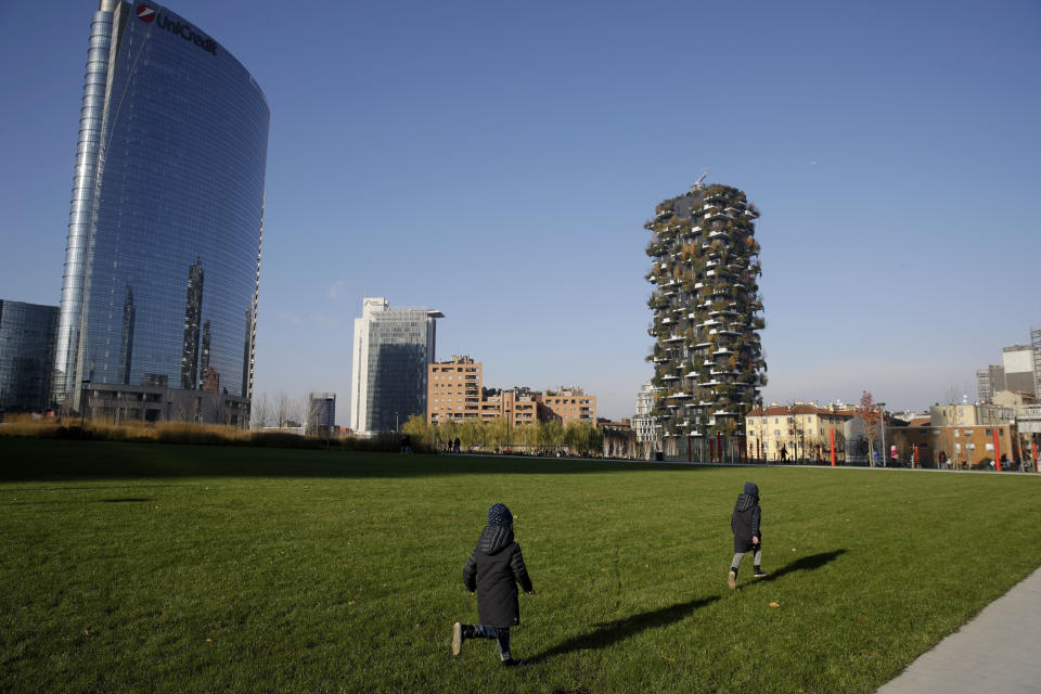 Children run on a field of the Tree Library park in Milan, Italy, Sunday, Dec. 9, 2018. If Italy's fashion capital has a predominant color, it is gray not only because of the blocks of uninterrupted neoclassical stone buildings for which the city is celebrated, but also due to the often-gray sky that traps in pollution. The city has ambitious plans to plant 3 million new trees by 2030_ a move that experts say could offer relief to the city’s muggy and sometimes tropical weather. (AP Photo/Luca Bruno)