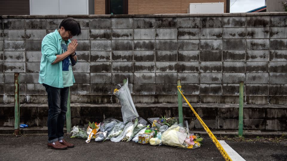 A man prays after laying flowers near the Kyoto Animation studio building after an arson attack on July 19, 2019 in Kyoto, Japan. - Carl Court/Getty Images