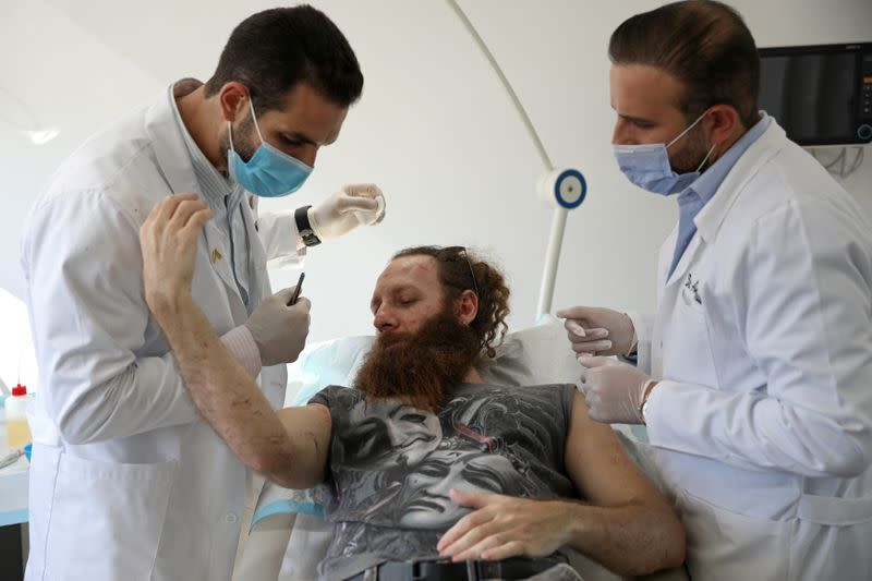 FILE PHOTO: Plastic surgeons Dr. Joe Baroud and Dr. Anis Mrad, who offer their services for free to people injured by a massive explosion at the port area, check the wounds of Shady Rizk, in Beirut