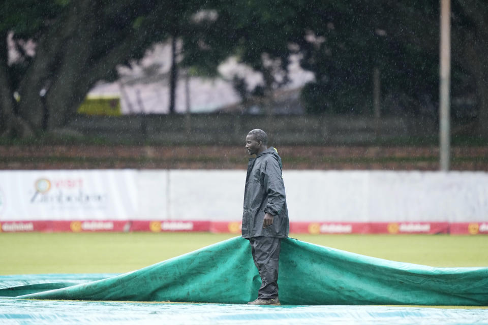 A groundsman stands in the rain on the first day of the Test cricket match between Zimbabwe and the West Indies, at Queens Sports Club in Bulawayo, Zimbabwe, Saturday, Feb. 4, 2023. (AP Photo/Tsvangirayi Mukwazhi)