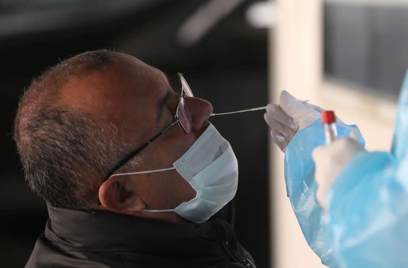 A health worker takes a swab from a man to be tested for the coronavirus disease (COVID-19) at a drive-through testing site, at American University of Beirut's (AUB) medical centr