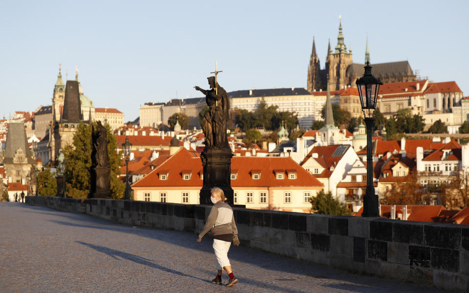 A woman wearing a face mask walks across the medieval Charles Bridge in Prague, Czech Republic, Friday, Sept. 18, 2020. The Czech Republic has been been facing the second wave of infections. The number of new confirmed coronavirus infections has been setting new records almost on a daily basis, currently surpassing 3,000 cases in one day for the first time. (AP Photo/Petr David Josek)