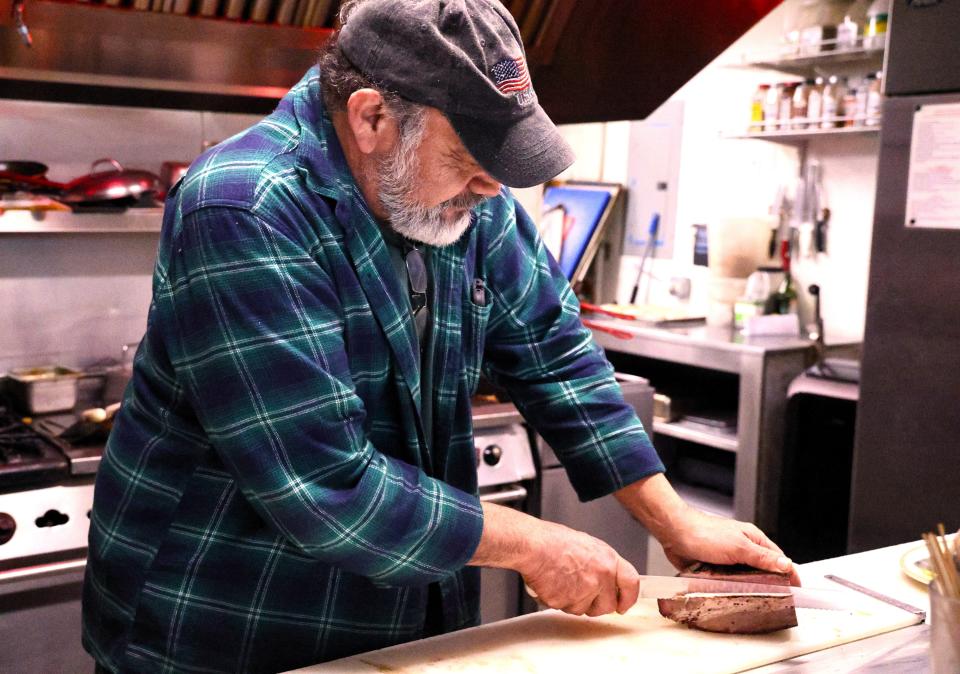 Old Mill Eatery & Smokehouse owner Fernando Perez cuts a brisket to make a brisket sandwich on Jan. 18, 2024 in Shasta Lake.