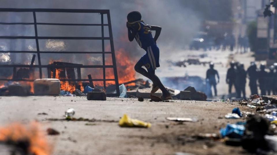 A boy walks past barricades as Senegalese protesters clash with riot police during a demonstration against the postponement of the February 25 presidential election in Dakar, Senegal