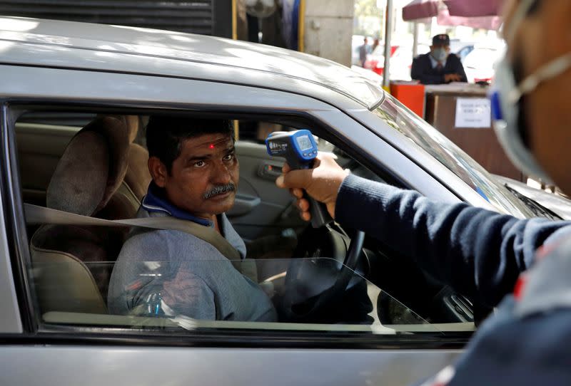 A man arriving into an office building gets his temperature measured by a private security guard using an infrared thermometer, following an outbreak of the coronavirus disease, in New Delhi