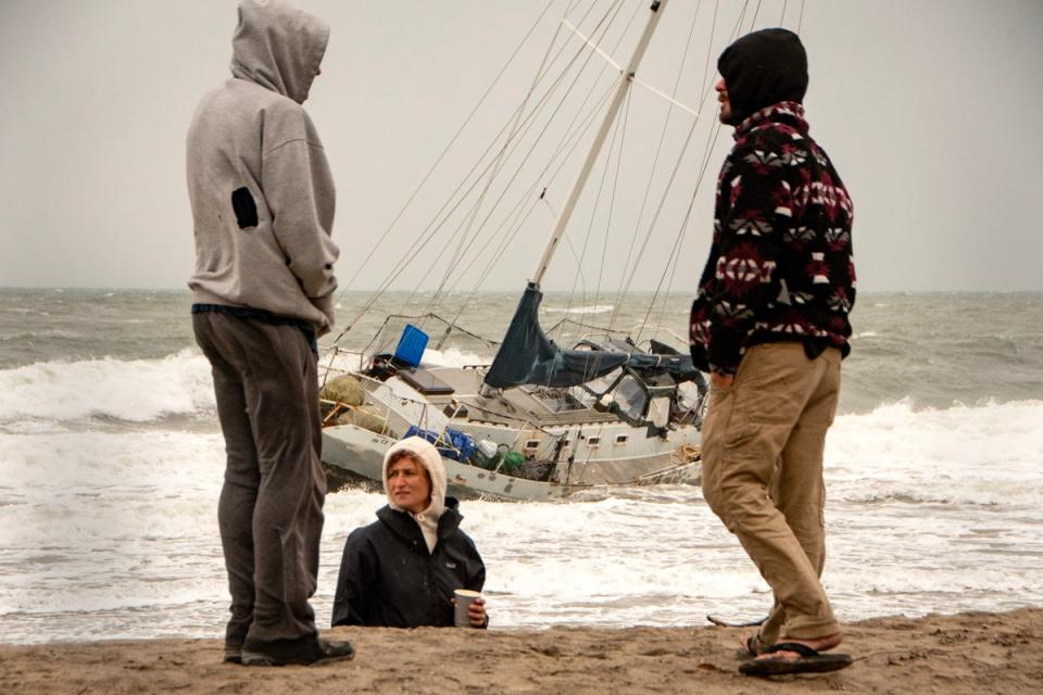 People stand next to a boat that washed ashore during an atmospheric river weather event in Santa Barbara, California (EPA)