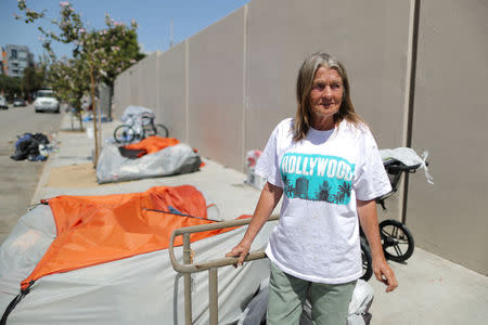 Vicki Dollar, 70, who has been homeless for a year with her son after he lost his job and they were evicted, stands next to her tent which they city requires her to take down during the day, in Hollywood, Los Angeles, California, U.S. April 13, 2018. Picture taken April 13, 2018. REUTERS/Lucy Nicholson