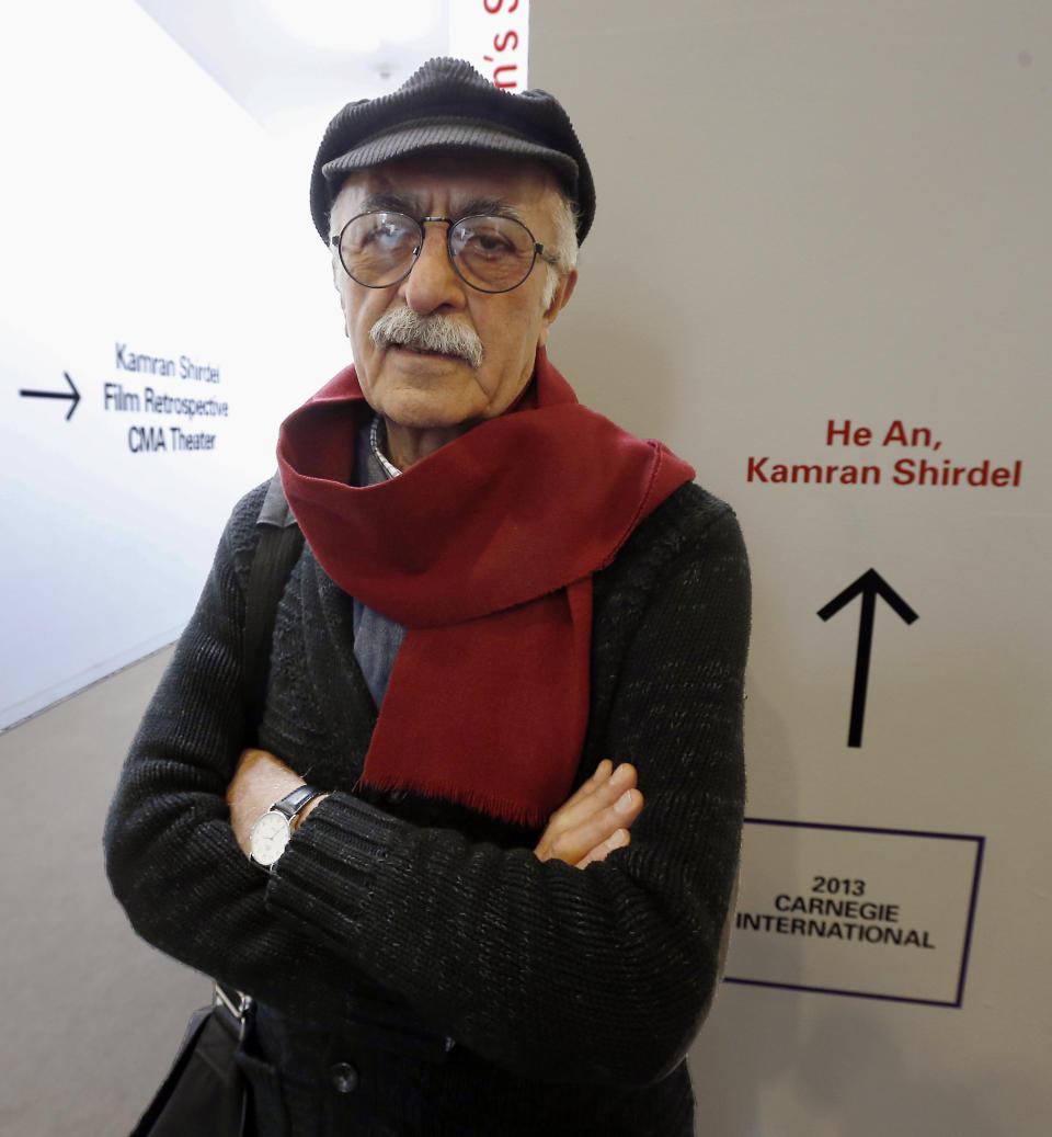 Iranian filmmaker Kamran Shirdel poses beside the sign pointing to where some of his films can be seen at the Carnegie Museum of Art Thursday, Feb. 20, 2014, during his first visit to the U.S. Shirdel began making gritty films of taboo subjects in the 1960s. (AP Photo/Keith Srakocic)