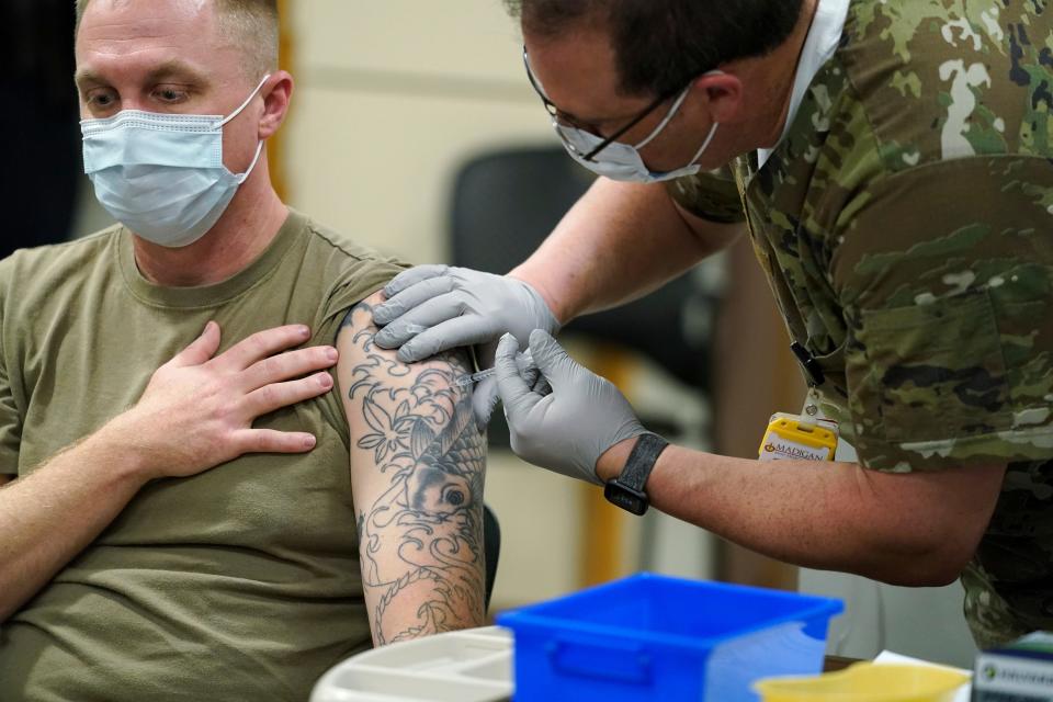 Staff Sgt. Travis Snyder, left, receives the first dose of the Pfizer COVID-19 vaccine given at Madigan Army Medical Center at Joint Base Lewis-McChord in Washington state, Dec. 16, 2020, south of Seattle.