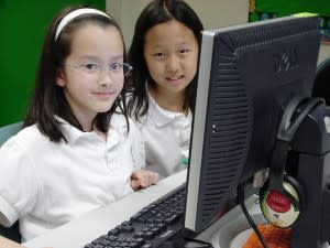 Two young girls using the computer